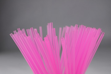 Pink plastic straws for use with drinks such as soft drinks, juices and alcohol on gray background