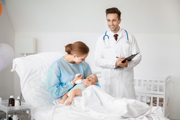 Young woman with newborn baby and gynecologist in maternity hospital