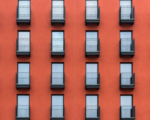 Front of a new red residential house with black balconies