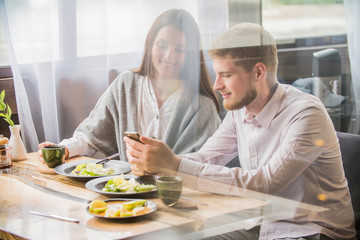key opinion leader millennial woman or girl makes selfie on smartphone   camera to share on internet social media channels.couple in a cafe   smiling looking at the phone