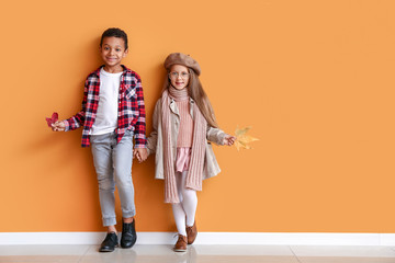 Naklejka premium Fashionable little children in autumn clothes near color wall