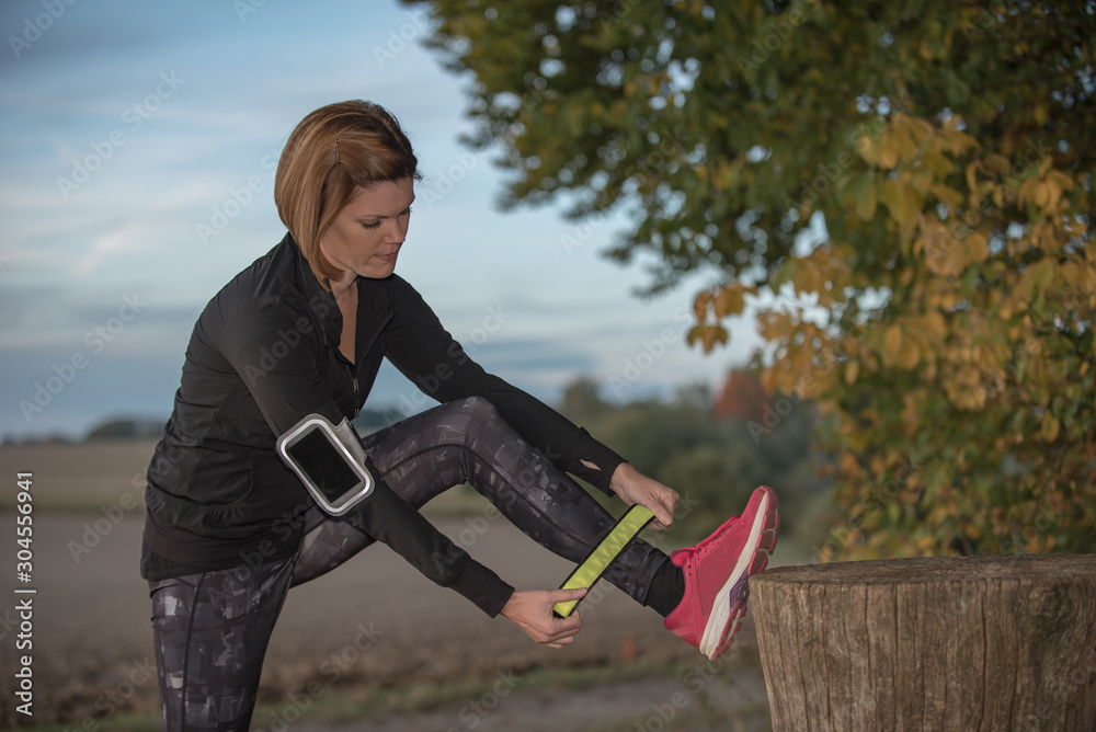 Wall mural young woman putting on safety led reflector before jogging