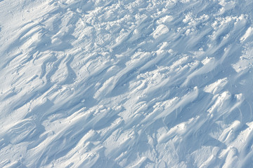 Fototapeta premium Snowy abstract off-piste skiing backround with ski and snowboard trails and tracks on new virgin powder snow. morning sunrise or evening sunset time at alpine mountain resort