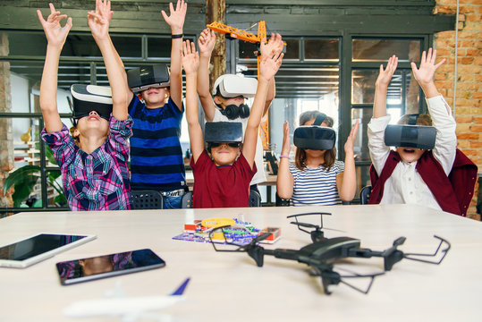 Korean scientist with the group of young pupils with laptop and VR headsets during a computer science class. Excited schoolchildren of smart modern primary school use augmented reality for studying
