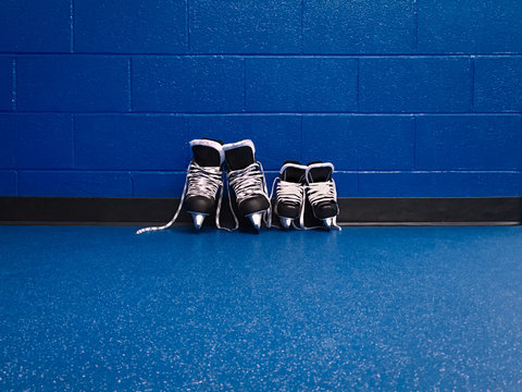 Hockey skates family adult and kid over floor in looker room with copy spac