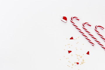 Modern Christmas background with candy canes, confetti and hat in red and white 