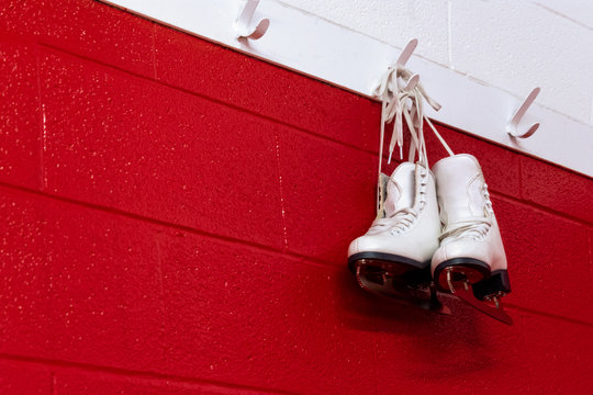 Figure skates hanging in locker room over red background with copy space 