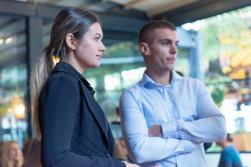 Two young male and female multiracial business people working connected with technological devices at the bar. Two young creative coworkers working with new startup project.