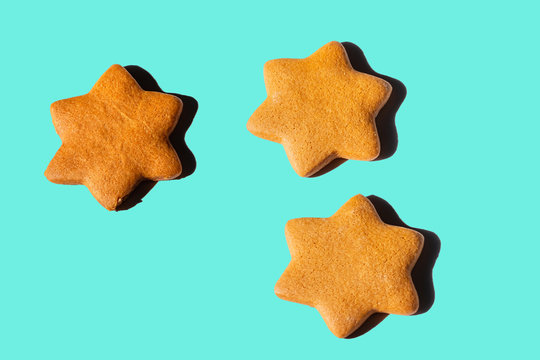 gingerbread stars on a wooden board with hard shadows on turquoise background
