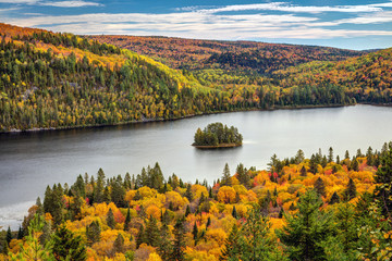 Pine Island in the middle of Wapizagonke lake surrounded by colorful forested hills in Autumn, La...