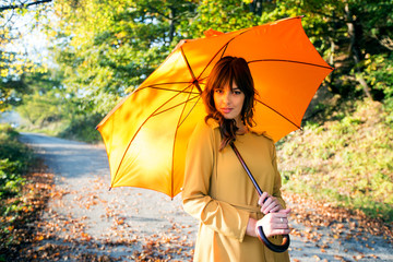 Portrait of fashionable woman with yellow umbrella at autumn day
