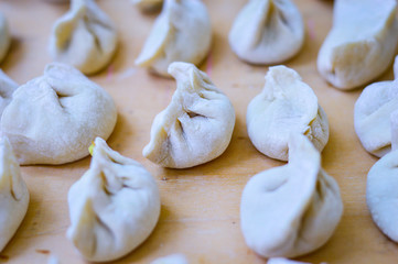 Close-up of Chinese Uncooked Dumplings Placed on Wooden Board.  The Dumplings, called Jiaozi in Chinese, is a popular traditional Chinese food, especially during Chinese New Year.