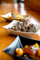 Grilled Chicken Ribs with Herb Garnish and other plates blurred in the foreground and background