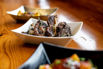 Grilled Chicken Ribs with Herb Garnish and other plates blurred in the foreground and background