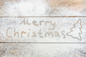 Merry Christmas-Christmas background with white flour and silhouette of Christmas tree with inscription. The view from the top .