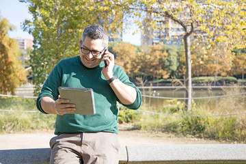 Businessman in a park talking attending a phone call
