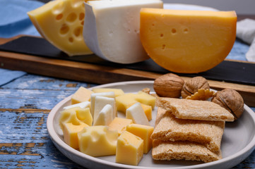 Tasty snacks, cheese blocks from Dutch yellow gouda and white goat hard cheeses and French holes cheese emmentaler