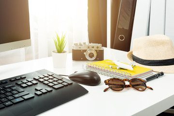 Travel planning concept at office with passports sunglases and computer.