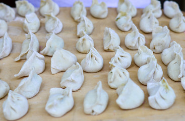 Fototapeta na wymiar Multiple Chinese Uncooked Dumplings Placed on Wooden Board. The Dumplings, called Jiaozi in Chinese, is a popular traditional Chinese food, especially during Chinese New Year.