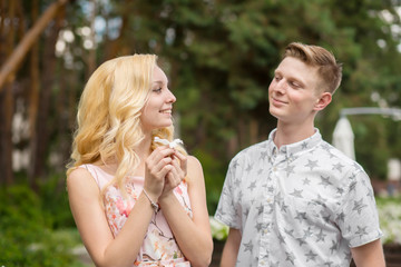 Fototapeta premium Young charming blonde girl is flirting and with a guy in the garden. Lovestory of a couple in love