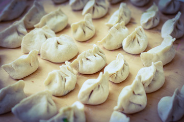 Chinese Uncooked Dumplings Placed on Wooden Board.  The Dumplings, called Jiaozi in Chinese, is a popular traditional Chinese food, especially during Chinese New Year.