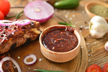 Tasty grilled meat with barbecue sauce, vegetables and spices on table