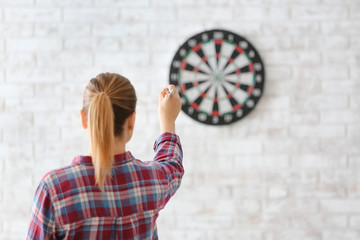 Young woman playing darts indoors
