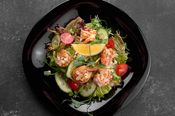 Vegetable salad with shrimp, on a black background