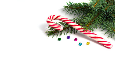 Christmas composition with fir tree branch, candy cane and colour bells isolated on white background