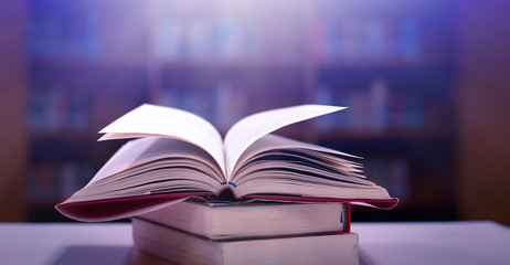 Stack of books in the library and blur bookshelf background