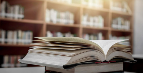 Stack of books in the library and blur bookshelf background