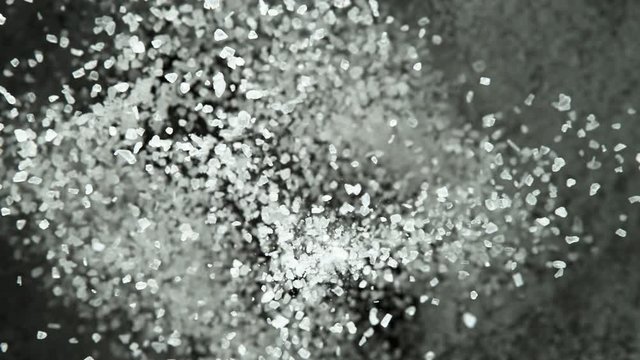 Super slow motion of flying whole grained salt pieces on black background. Filmed on high speed cinema camera, 1000 fps