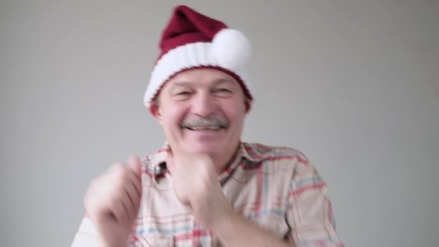 Happy Senior Hispanic Man In Christmas Red Hat Dancing Being Happy That It Is Holidays.