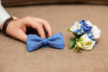 Groom takes his tie. Groom's morning. Wedding accessories in blue colors. Tie-butterfly and...