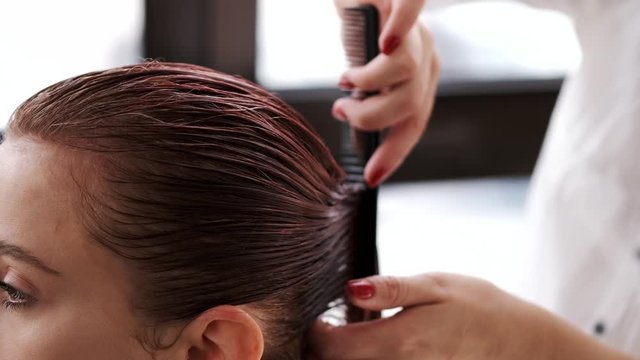 The hairdresser is combing the client's hair. Girl's hair is pink. The girls are in the beauty salon.