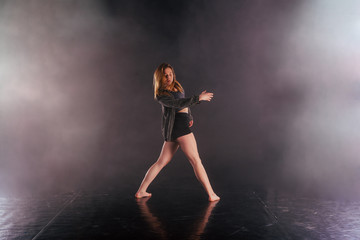 Shoeless female dance shows off her modern art dance moves while looking serious and devoted.
