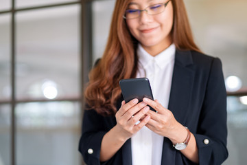 Obraz na płótnie Canvas Closeup image of a businesswoman holding and using mobile phone
