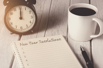 New Year's Resolutions List written on Notebook with alarm clock, pen, coffee