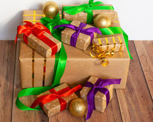 Gifts are packed in kraft paper and tied with a satin ribbon with New Year's toys on a wooden background. Surprise at the holiday. Toys for the Christmas tree..