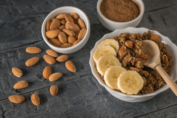 Scattered almonds, quinoa porridge with banana on a rustic table. Flat lay.