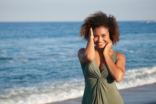 Stunning young bi-racial woman in green dress on beach at sunset - Powered by Adobe