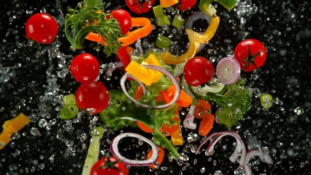 Super Slow Motion Shot of Flying Cuts of Colorful Vegetables and Water Drops on Black background at 1000fps.
