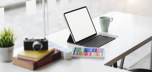 Cropped shot of modern graphic designer workplace with blank screen digital tablet, camera and office supplies