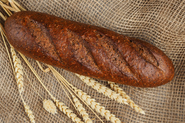 Loaf of fresh rye grain bread on burlap, top view