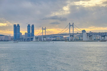 Scenic view of awesome sunset over modern bridge, sea and skyscrapers in Busan in South Korea. Beautiful summer cloudy look of evening in relax place in resort city of Republic of Korea