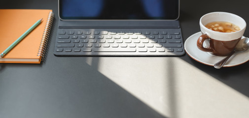 Cropped shot of modern office room with digital tablet, office supplies and a cup of tea