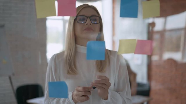focused business woman takes notes on stickers. Modern office. Success concept 4K