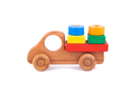 Close-up Children's Toy Made Of Natural Wood In The Form Of A Dump Truck  With Wooden Blocks In The Form Of Multi-colored Geometric Shapes On A White Isolated Background.