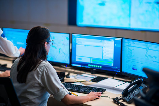 Female security guards working in surveillance room, monitoring cctv and discussing.