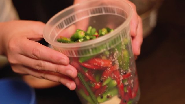 Mixing chilly and string beans in a container with vinegar Filipino style.